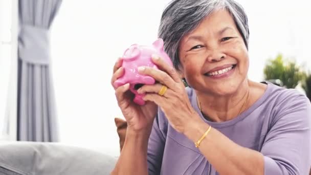 Vrolijke Aziatische Senior Vrouw Schudden Piggy Bank Glimlachend Camera Portret — Stockvideo