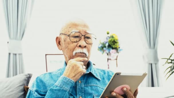 白い口ひげを用いたアジア シニア男自宅のコンピューター技術との祖父の幸せを手にタブレットします スローモーション ドリー ショット — ストック動画