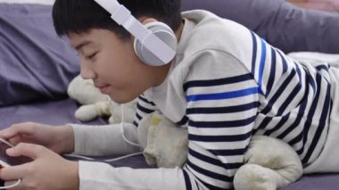 Tablet bilgisayarda izlemek ve gülümsemek yüz beyaz kulaklık giyen Asya yakışıklı UHD Dolly ateş.