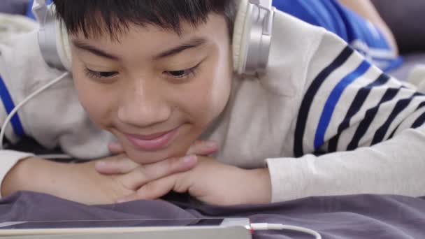 Uhd Dolly Disparar Asiático Lindo Chico Viendo Tableta Uso Auriculares — Vídeos de Stock