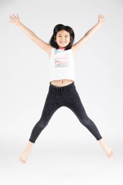 Asian funny child girl jumping on gray background. clipart