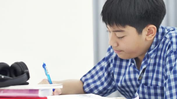 自宅で笑顔で宿題をしているアジアのかわいい男の子 4Kドリーショット — ストック動画