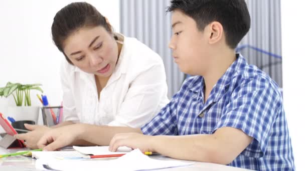 アジアの若い母親教育の息子は自宅 宿題を笑顔でテーブルの上の息子とアジアの母 ドリー ショット — ストック動画