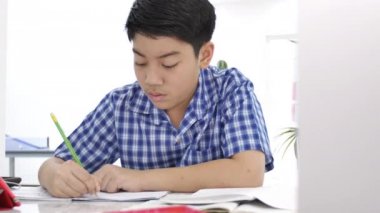 Asya sevimli çocuk evde gülümseme yüz ile ev ödevi yapıyor, 4k Dolly atış.