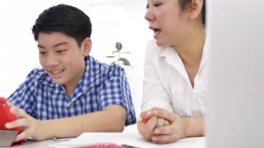 Anne ve oğlu oynamak ve smartphone, izlerken mutlu Asya ailesi ile gülen yüz evde çekim Dolly .