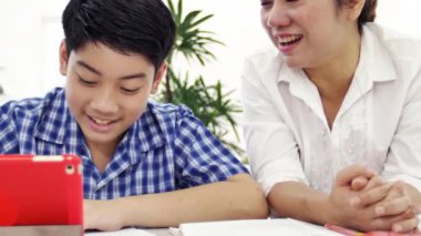 Genç Asyalı anne öğretim oğlum evde. Asya anne oğluyla gülümsemek yüz ile tabloda ödev. 4 k vurdu dolly