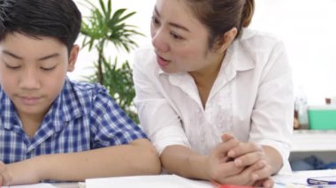 Genç Asyalı anne öğretim oğlum evde. Asya anne oğluyla gülümsemek yüz ile tabloda ödev. 4 k vurdu dolly