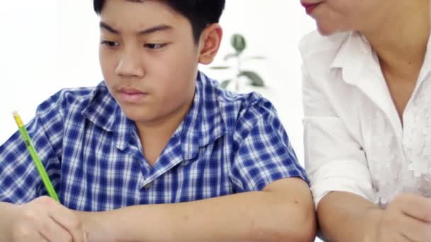 年轻的亚洲母亲在家教儿子 亚洲妈妈带着儿子在桌子上做作业 面带微笑 多利射门4K — 图库视频影像