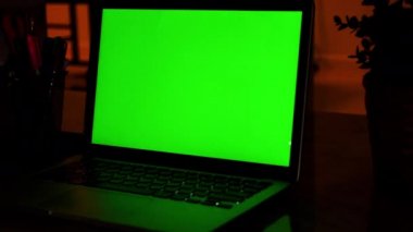 Yeşil Renk Anahtar Ekranı Gösteren Dizüstü Bilgisayar Oturma Odasında Bir Masa Üzerinde Duruyor. Arka Planda Sıcak Işıklar açık Akşam Rahat Oturma Odası. Dolly sağdan sola vurdu. 4k