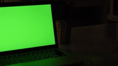 Yeşil Renk Anahtar Ekranı Gösteren Dizüstü Bilgisayar Oturma Odasında Bir Masa Üzerinde Duruyor. Arka Planda Sıcak Işıklar açık Akşam Rahat Oturma Odası. Dolly sağdan sola vurdu. 4k