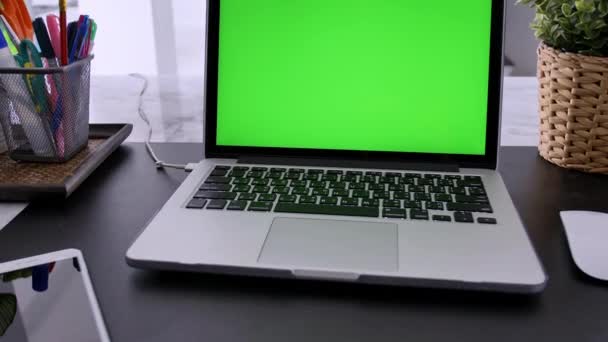リビングルームの机の上に緑色のクロマキースクリーンを表示するラップトップコンピュータ 背景に居心地の良いリビングルームで — ストック動画