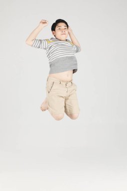 Asian funny child boy jumping on gray background. clipart