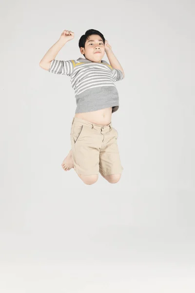 Asiatische lustige Kind Junge springen auf grauem Hintergrund. — Stockfoto