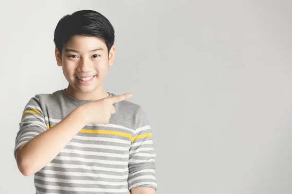 Asiatiska preteen Teenage Boy pekar upp över grå bakgrund. — Stockfoto