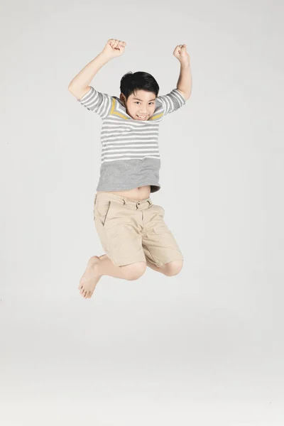 Asiático engraçado criança menino pulando no fundo cinza . — Fotografia de Stock