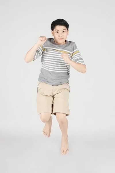 Aziatische grappig kind jongen springen op grijze achtergrond. — Stockfoto