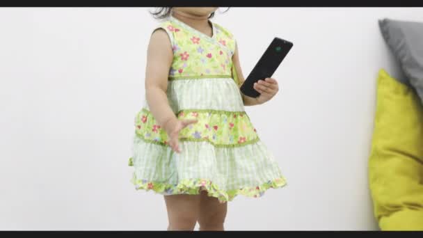 Ευτυχισμένο Ασιατικό Μωρό Κορίτσι Τηλεχειριστήριο Στο Σαλόνι Χειρός Χαρούμενο Παιδί — Αρχείο Βίντεο