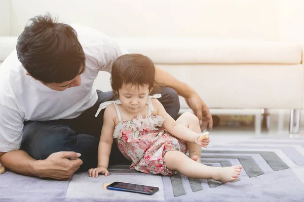 Evde cep telefonu kullanan bir baba ve küçük kızının görünümü . — Stok fotoğraf
