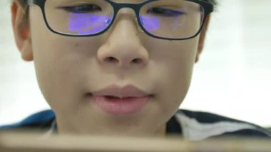 Gözlük refleks mavi kutu ile akıllı telefonda oyun oynayan genç asyalı çocuk yakın .