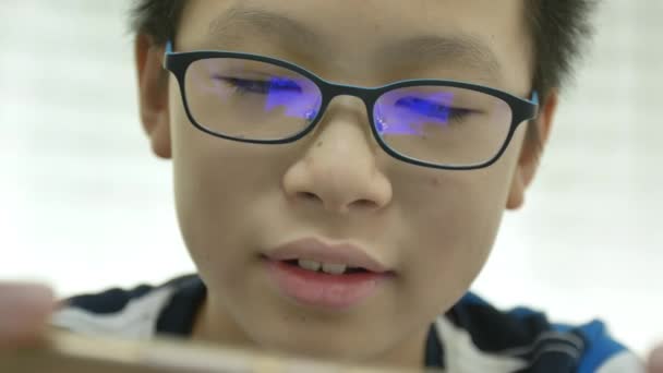 年轻的亚洲男孩在智能手机上玩游戏的特写镜头 眼镜上有反射蓝盒 — 图库视频影像