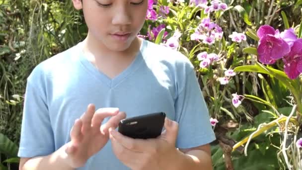 Счастливый Азиатский Мальчик Сфотографироваться Красивым Цветком Орхидеи Саду — стоковое видео