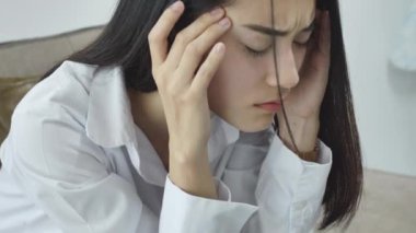 Asyalı kadın ofiste işten stres hissediyor. Ofiste ki işyerinde yorgun iş kadını başını elleri üzerinde tutarak baş ağrısı hissediyor.