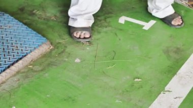 El adam ayaklar sandal yaklaşımı çöp, sonra bir adam bir kepçe içine odun tozu süpürüyor. Çalıştıktan sonra atölyede temizlik.