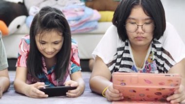 Evde tablet veya akıllı telefon oynayan çocuk , Asyalı erkek ve kız gülümseme yüz ile birlikte cep telefonu oyunu oynuyor.