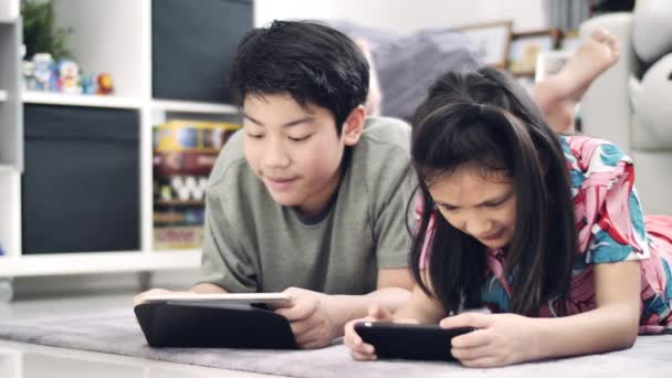 Barn Leker Med Tablet Eller Smartphone Hemma Asiatiskapojke Och Flicka — Stockvideo