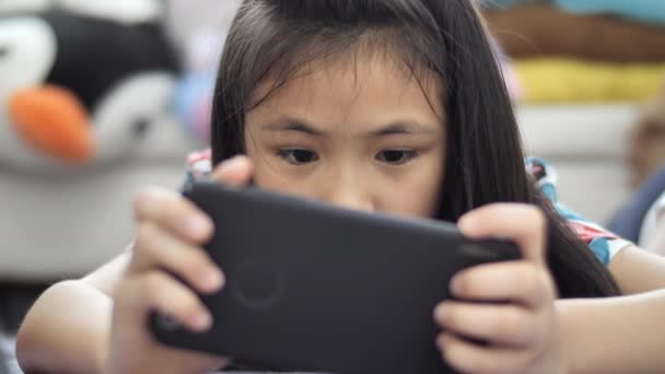 女孩玩平板电脑或智能手机在家里 亚洲女孩玩手机游戏与微笑的脸 — 图库视频影像