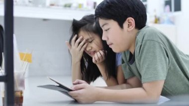 Evde tablet veya akıllı telefon oynayan çocuk , Asyalı erkek ve kız gülümseme yüz ile birlikte cep telefonu oyunu oynuyor.