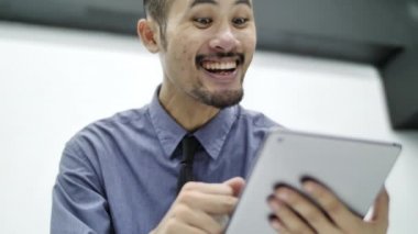 Stajyer ofis adamı tablet le bir mesaj veya arama gönderir ve gülümsüyor. Kavram : sosyal ağ, mesaj, teknoloji.