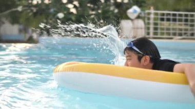 Mutlu asyalı çocuk gülümseme yüz ile yüzme havuzunda oynarken