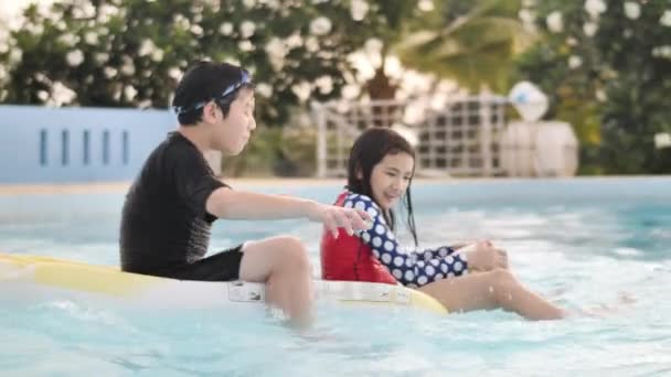 スイミングプールでかわいい子供 笑顔でプールで遊ぶアジアの幸せな兄弟姉妹 — ストック動画