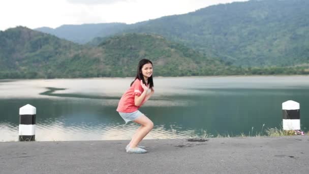 幸福的亚洲女孩的肖像是跳跃与美丽的微笑在自然景色中间 — 图库视频影像