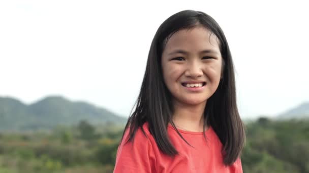 丘の中腹公園で楽しい遊び心を楽しんで笑顔陽気なアジアの女の子のクローズアップポートレート — ストック動画