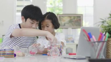 Genç asyalı erkek ve kız gülümseme yüzü ile yapboz ile oynuyor. Ev el sanatları. Dolly atış 60fps.