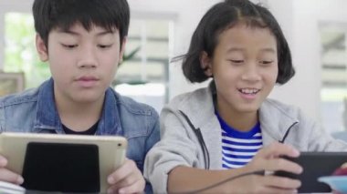Yakın asya sevimli kız ve genç erkek akıllı telefonlar ve tablet rekabetçi video oyunu oynarken, yatay manzara modunda onları tutarak. Dolly Shot 60fps.
