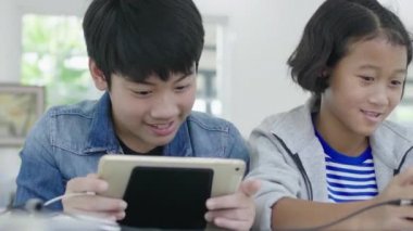 Yakın asya sevimli kız ve genç erkek akıllı telefonlar ve tablet rekabetçi video oyunu oynarken, yatay manzara modunda onları tutarak. Dolly Shot 60fps.