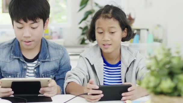 特写亚洲可爱的女孩和小男孩在智能手机和平板电脑上玩竞争视频游戏 在水平景观模式举行他们 60Fps在娃娃射击 — 图库视频影像