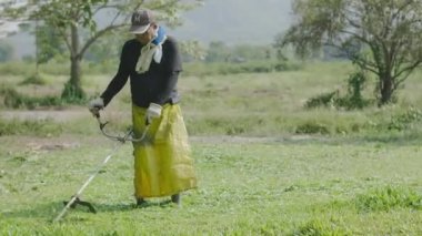 Yaşlı adam ön bahçede çim biçme makinesi kullanıyor. Bahçıvan çim biçme makinesiyle çim leri kesiyor. 60fps