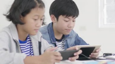 Yakın asya sevimli kız ve genç erkek akıllı telefonlar ve tablet rekabetçi video oyunu oynarken, yatay manzara modunda onları tutarak. Dolly Shot 60fps.