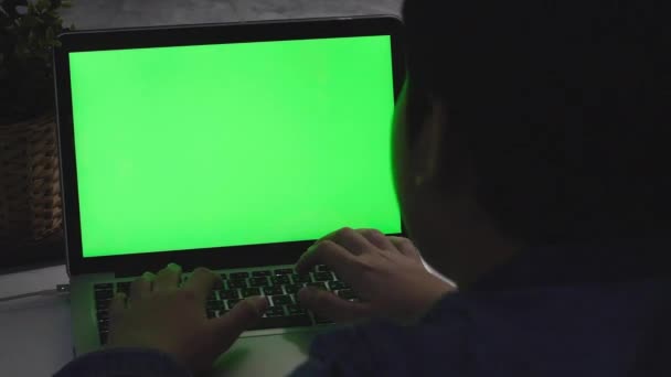 机の上のノートパソコンで使っている少年の肩越しに 緑色の画面を見る ドリーショット60Fps — ストック動画