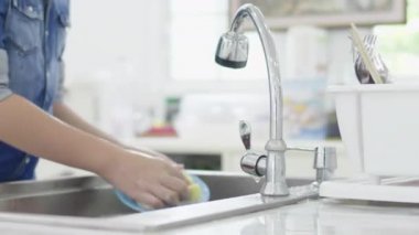 Asyalı genç çocuk evde mutfakta bulaşık yıkama, yaşam tarzı kavramı. Tayland modern evde lavaboda Genç yıkama çanak. 60fps