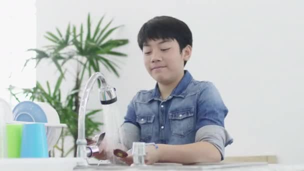 家庭の台所で皿を洗うアジアの若い男の子 ライフスタイルのコンセプト タイの近代的な家の流しで十代の洗濯皿 60Fps — ストック動画
