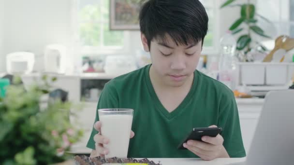 Asian Young Boy Using Scrolls Smartphone Applications While Slowly Eats — Stock Video