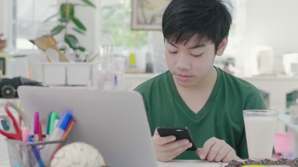 Asian Young Boy Using Scrolls Smartphone Applications While Slowly Eats — Stock Video