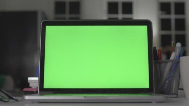 Yeşil ekranlı dizüstü bilgisayar. Karanlık ofis. Dolly vuruldu. Kendi resminizi veya videonuzu koymak için mükemmel.