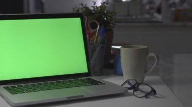 Yeşil ekranlı dizüstü bilgisayar. Karanlık ofis. Dolly vuruldu. Kendi resminizi veya videonuzu koymak için mükemmel.