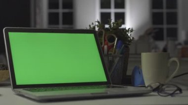 Yeşil ekranlı dizüstü bilgisayar. Karanlık ofis. Dolly vuruldu. Kendi resminizi veya videonuzu koymak için mükemmel.